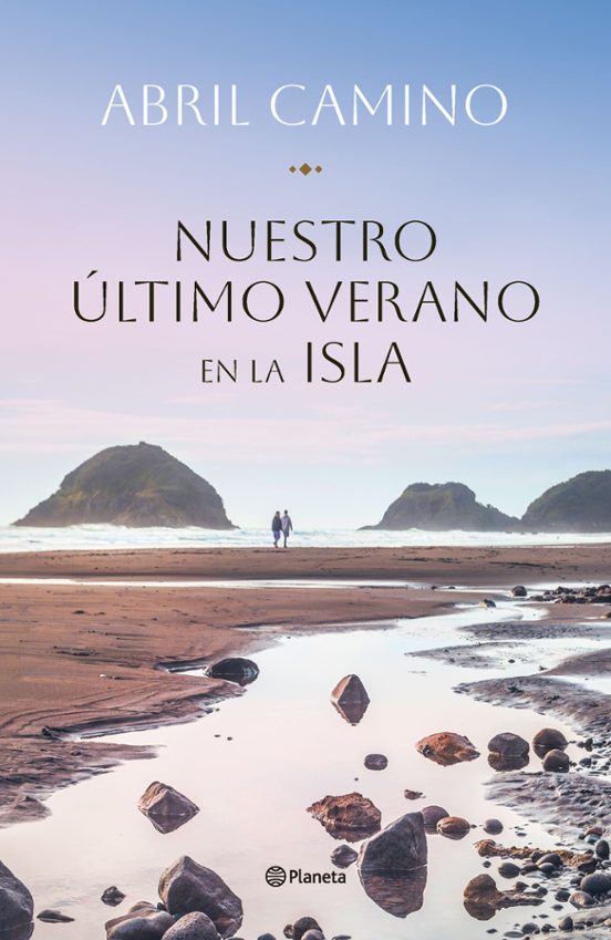 Platja d'una isla, amb sorra, roques, pedres i un petit riu que desemboca al mar. Al fos, podem observar dues persones a l'horitzó.